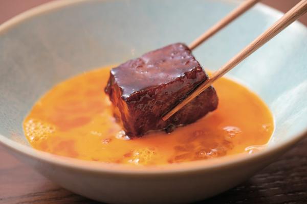 A cube of simmered wagyu dipped in raw egg