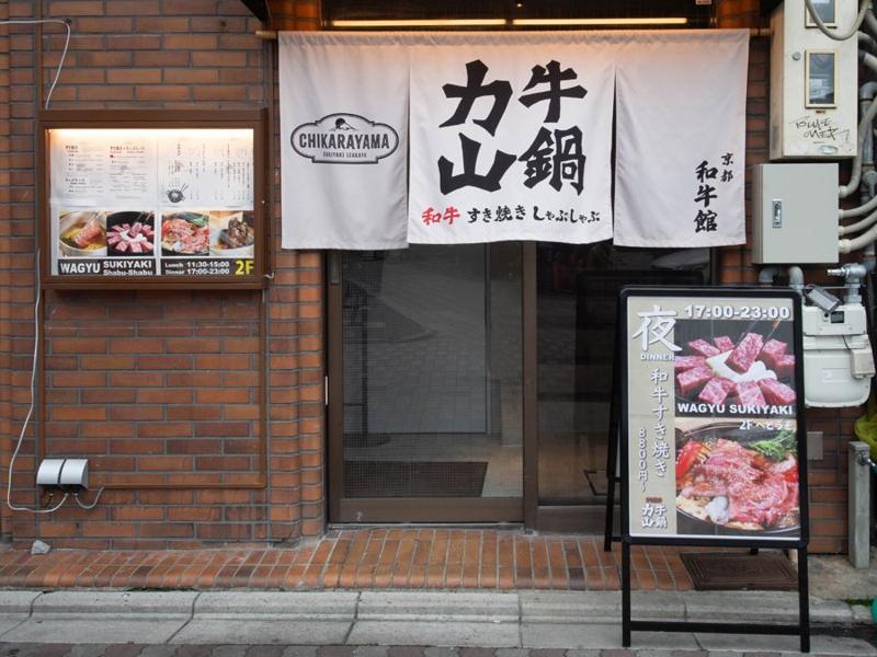 Chikarayama Shijo Kawaramachi entrance with white noren curtain on a brick wall